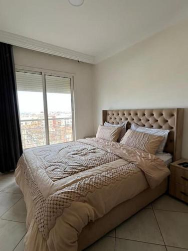 a bedroom with a large bed with a large window at Appartement Chaleureux et Cosy Proche De sortie autoroute in Mohammedia