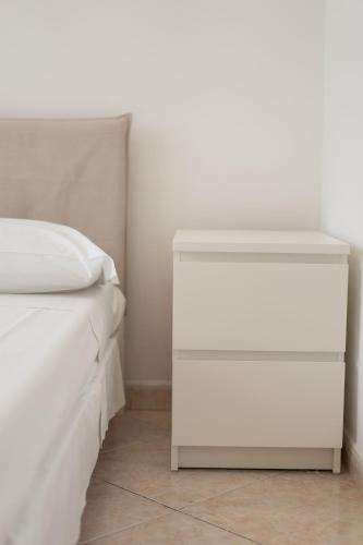 a white bed with a white nightstand next to it at Capodichino Airport Home By Dimorra in Naples