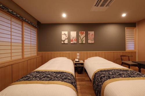 two twin beds in a room with two tables at Mutsumikan in Gero