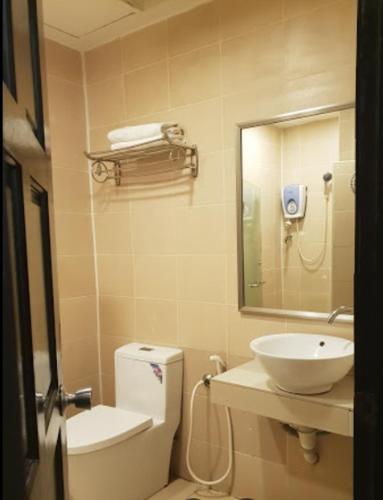 ein Badezimmer mit einem Waschbecken, einem WC und einem Spiegel in der Unterkunft Kingston Executive Hotel in Tawau