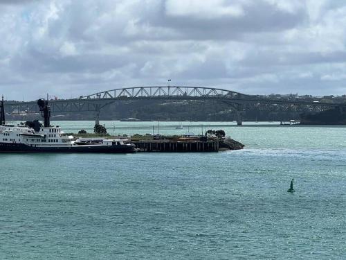 un bateau dans l'eau avec un pont en arrière-plan dans l'établissement Waterfront Seaview Hotel Apartment - same building block as Auckland Hilton, à Auckland