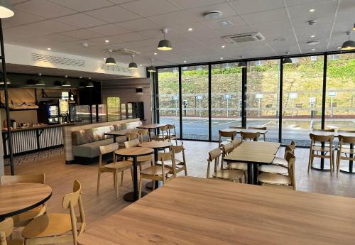 um restaurante com mesas e cadeiras de madeira e janelas em B&B HOTEL Besançon Valentin em Besançon