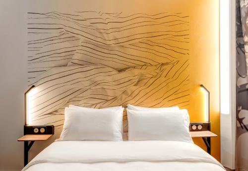 - une chambre avec un grand lit et une tête de lit en bois dans l'établissement B&B HOTEL Besançon Valentin, à Besançon