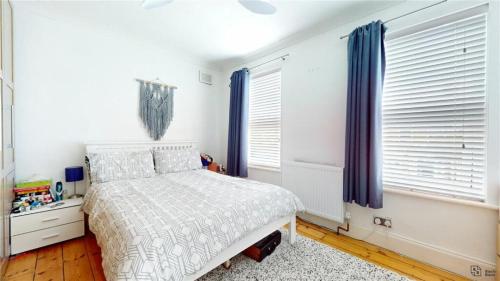 een slaapkamer met een bed en twee ramen bij Charming 2-Bedroom Flat in the Heart of Cro London ER1 in South Norwood