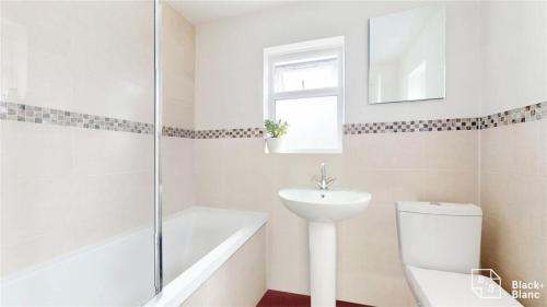 Baño blanco con lavabo y aseo en Charming 2-Bedroom Flat in the Heart of Cro London ER1 en South Norwood