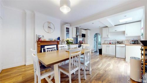 a kitchen and dining room with a wooden table and chairs at Charming 2-Bedroom Flat in the Heart of Cro London ER1 in South Norwood