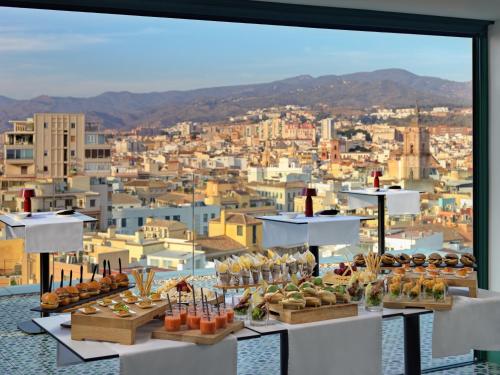 a display of food on a table with a view of a city at H10 Croma Málaga in Málaga