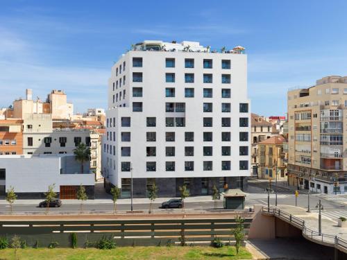 a tall white building in a city with a bridge at H10 Croma Málaga in Málaga