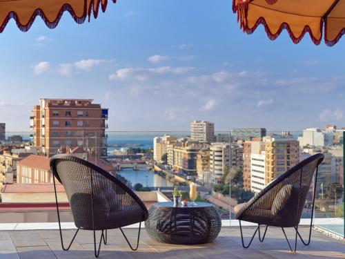two chairs and a table on a balcony with a view at H10 Croma Málaga in Málaga
