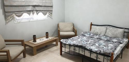 a bedroom with a bed and a chair and a table at HOUSE IN AL AIN in Al Ain