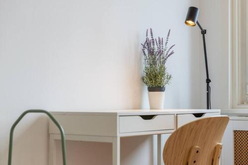 a white desk with a potted plant and a lamp at Midtown Gleaming Apartment in Budapest
