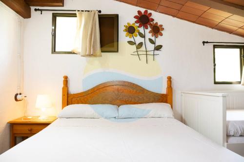 デルテブレにあるMas de Felip - Casa rural con piscina privada en el Delta - Deltavacacionesの白いベッド1台、壁に花が飾られたベッドルーム1室