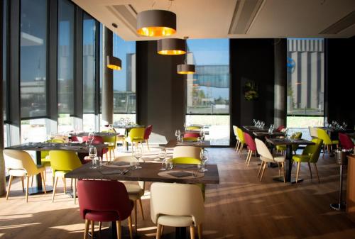 - un restaurant avec des tables, des chaises et de grandes fenêtres dans l'établissement YParc Hôtel, à Yverdon-les-Bains