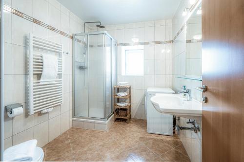 a bathroom with a glass shower and a sink at Panorama Spa Lodges DAS.SCHILLER in Bad Gastein