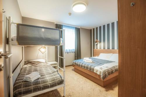 a hotel room with a bed and a bunk bed at Panorama Spa Lodges DAS.SCHILLER in Bad Gastein