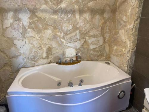a bath tub in a bathroom with a stone wall at Amman landscape farm in Amman