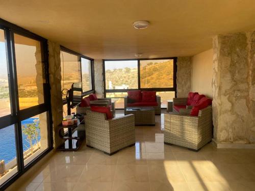 a living room with couches and tables and windows at Amman landscape farm in Amman