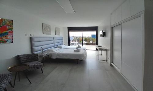 een slaapkamer met een bed, stoelen en een raam bij VillasRoyale Diamante in San Bartolomé