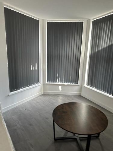 sala de estar con mesa y 3 ventanas grandes en 1GS Luxury London Road Apartments en Leicester