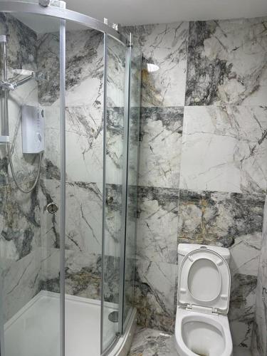 a marble bathroom with a toilet and a shower at 1GS Luxury London Road Apartments in Leicester