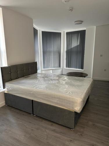 a large bed in a room with two windows at 1GS Luxury London Road Apartments in Leicester