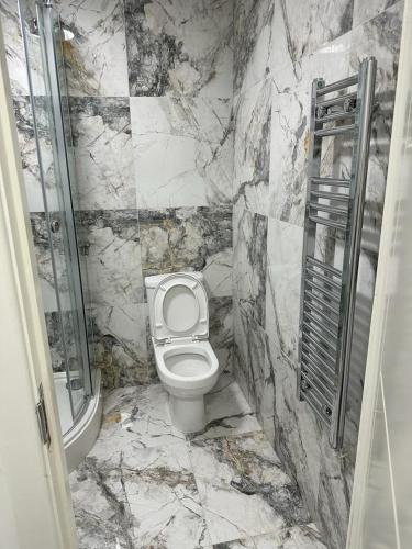 a marble bathroom with a toilet and a shower at 1GS Luxury London Road Apartments in Leicester