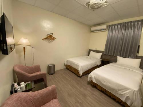 una habitación de hotel con 2 camas y una silla en 東石民宿 湛藍海寓 Azure Seaside House, en Dongshi