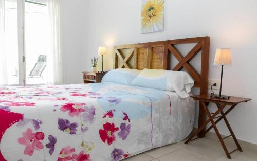 a bedroom with a bed with a floral bedspread at Baconer - Casa en l'Ampolla con jardín privado y acceso directo al mar - Deltavacaciones in L'Ampolla