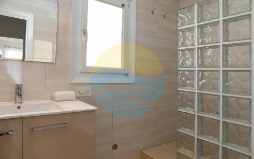 a bathroom with a sink and a window and a shower at Baconer - Casa en l'Ampolla con jardín privado y acceso directo al mar - Deltavacaciones in L'Ampolla