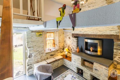 un salon avec un mur en pierre et une cheminée dans l'établissement Le Pont de Benneville, à Cahagnes