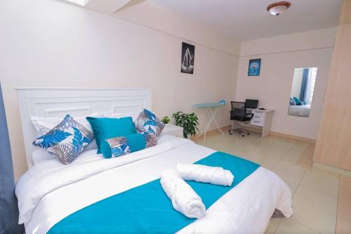 a bedroom with a large bed with blue and white pillows at LaMeg furnished 1 bedroom Garden Estate in Nairobi