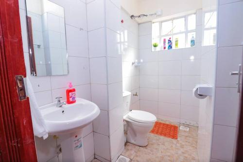 a white bathroom with a sink and a toilet at LaMeg furnished 1 bedroom Garden Estate in Nairobi