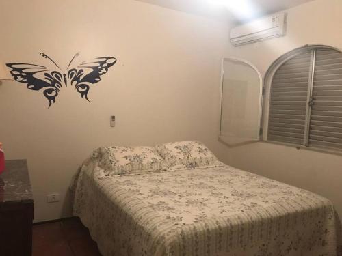 um quarto com uma cama e um estêncil de borboleta na parede em Apartamento muito charmoso na praia da Enseada no Guarujá