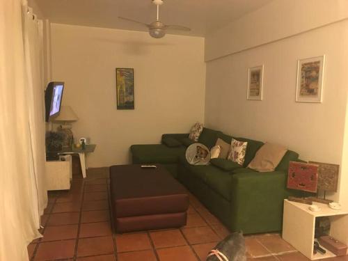 uma sala de estar com um sofá verde e uma televisão em Apartamento muito charmoso na praia da Enseada no Guarujá