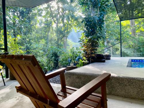 a wooden chair sitting on a patio with a pool at Balai Benedicere Bed & Breakfast in Bacnotan