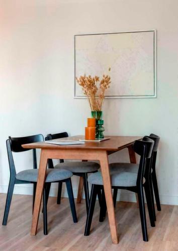 een eettafel met stoelen en een vaas met bloemen bij Spacious and Stylish 3-Bedroom Flat in Cro, London ER2 in South Norwood