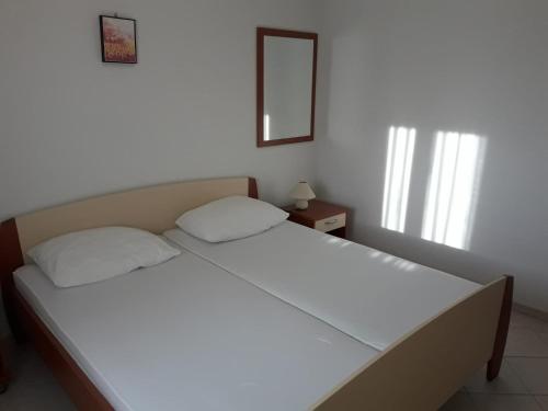 a bed with white sheets and a mirror in a bedroom at Apartmani Manuela Ljubač in Ljubač