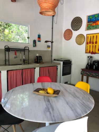 a kitchen with a table with a plate of fruit on it at Casa Pintassilgo mini in Santa Cruz Cabrália