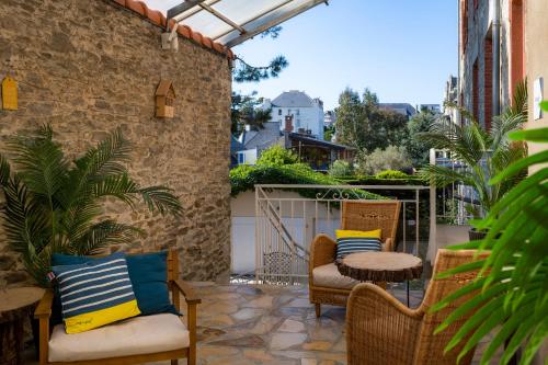 a patio with chairs and a table and a fence at VTF L'Hotel Des Bains in Saint-Cast-le-Guildo