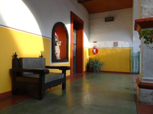 un salon avec une chaise et un mur jaune dans l'établissement Hotel Principal, à Oaxaca