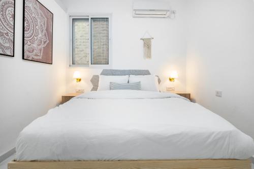 een witte slaapkamer met een groot bed met witte lakens bij Moroccan style apartment near Bahai Gardens in Haifa