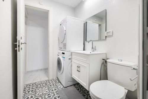 a white bathroom with a toilet and a sink at Moroccan style apartment near Bahai Gardens in Haifa