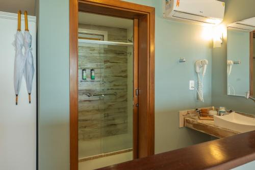 a bathroom with a shower with a sink and a mirror at Pousada Dona Moça in Morro de São Paulo