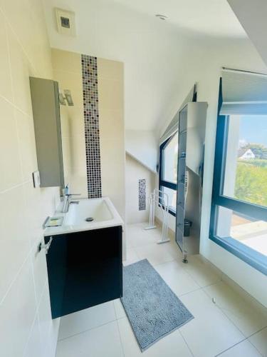 La grande salle de bains est pourvue d'un lavabo et d'une fenêtre. dans l'établissement L'écrin marin : Vue exceptionnelle sur l'Océan, à Batz-sur-Mer