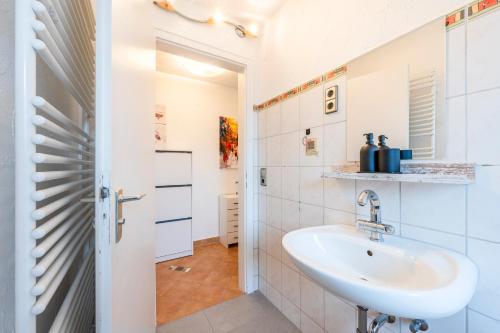 baño con lavabo y pared de azulejos blancos en EXQUIS 2,5 BR Maisonette I Familien I TOP-Location I Netflix I Mercedes-Benz, en Böblingen