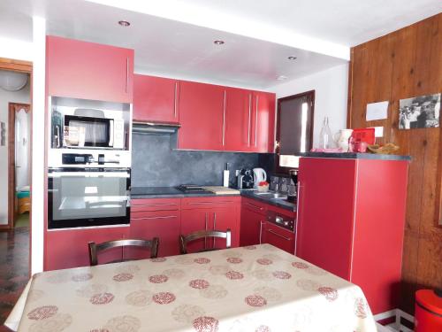 - une cuisine avec des placards rouges et une table dans l'établissement Appartement idéal 4-5 pers. près des pistes - Le Chinaillon - FR-1-467-79, au Grand-Bornand
