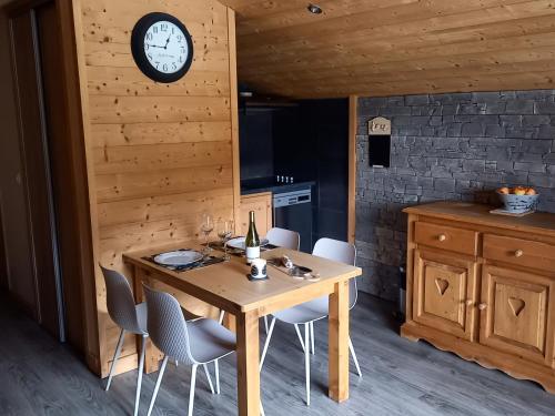 une cuisine avec une table, des chaises et une horloge murale dans l'établissement Appartement cosy avec balcon sud, proche pistes ski, animaux admis, parking privé, draps inclus - FR-1-467-113, au Grand-Bornand