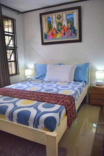 a bedroom with a bed with a painting on the wall at Cozy 1-bedroom house in quiet residential village. in Iloilo City