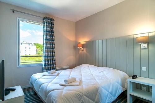 um quarto com uma grande cama branca e uma janela em Les Thermes 511 - Appt proche plage avec piscine partagée em Concarneau
