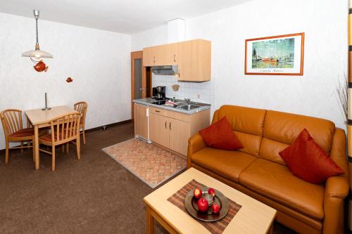 ein Wohnzimmer mit einem Sofa, einer Küche und einem Tisch in der Unterkunft Haus Sonneck, App 2 in Duhnen